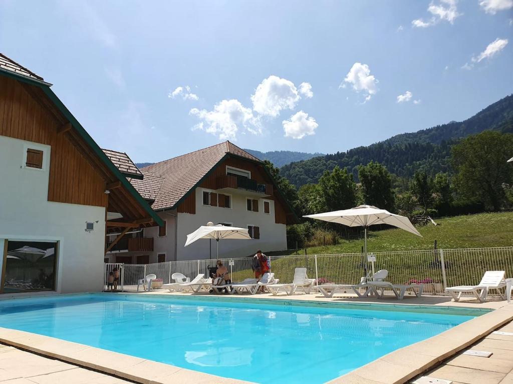 a swimming pool with chairs and umbrellas next to a building at Studio dans résidence de tourisme*** in Giez
