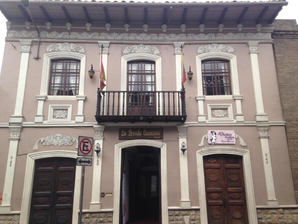 ein rosafarbenes Gebäude mit einem Balkon und zwei Türen in der Unterkunft La Posada Cuencana Hotel Boutique in Cuenca