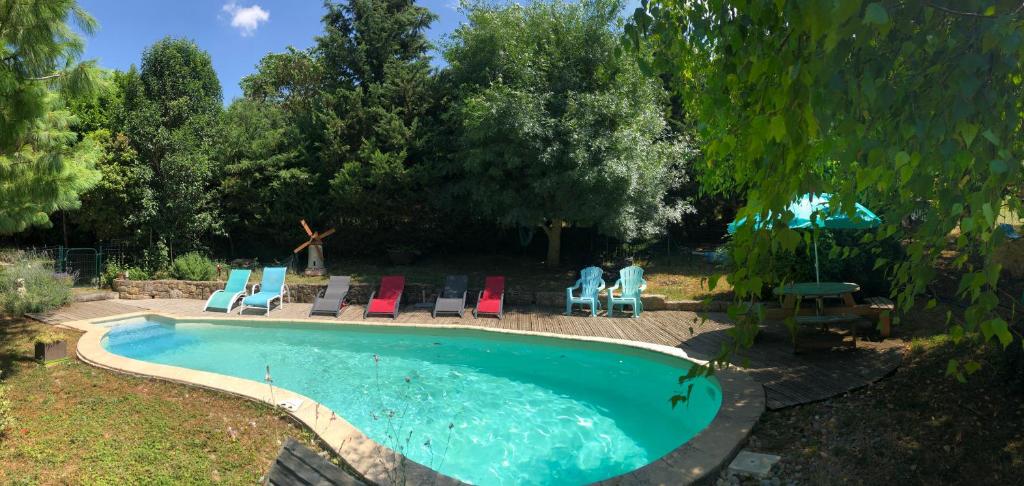 a swimming pool with chairs and people sitting around it at Gîte Au Coeur Du Pays Cathare in Fanjeaux