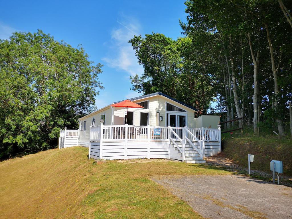 a small white house with an orange umbrella on a hill at Trevellian - Boutique Secluded Scenic Lodge in Dawlish