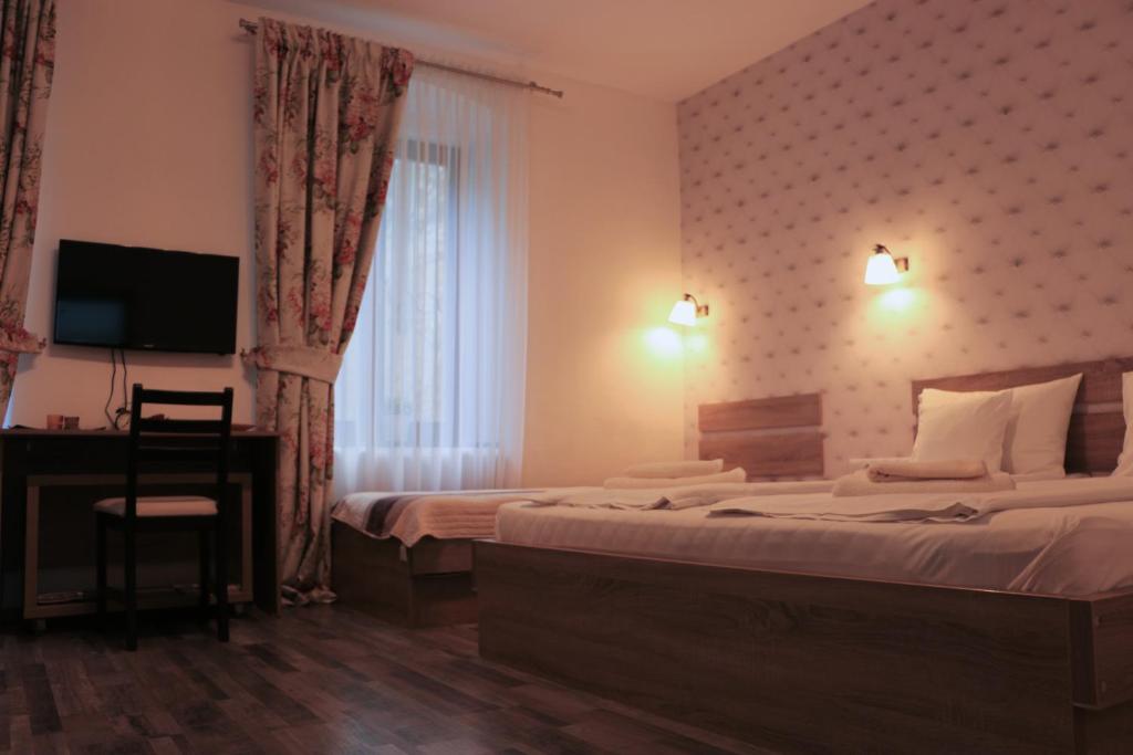 Corso Comfort Apartments في سيبيو: غرفة فندقية فيها سرير ومكتب وتلفزيون