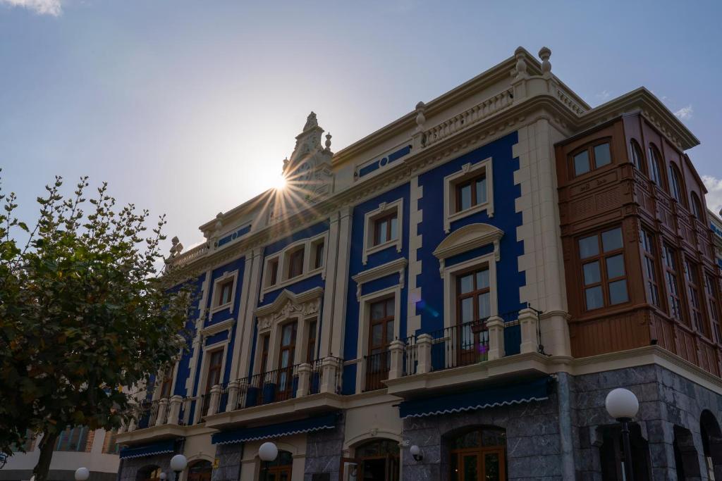 un edificio azul con el sol brillando en él en Puente Colgante Boutique Hotel, en Portugalete