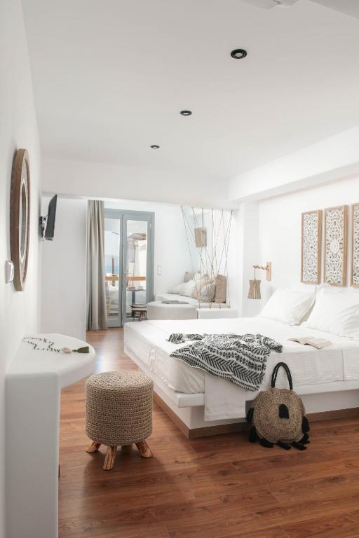 a white bedroom with a large bed and a table at Kissos Luxury Suites in Naxos Chora