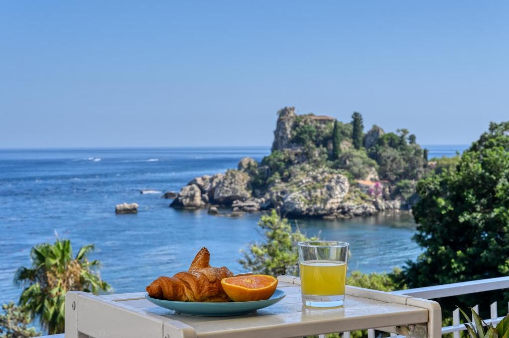 una mesa con un plato de comida y un vaso de zumo de naranja en Paradisea Taormina, en Taormina
