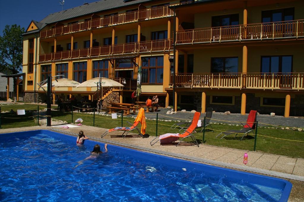 a swimming pool in front of a hotel with people in it at Hotel Avalanche in Štôla