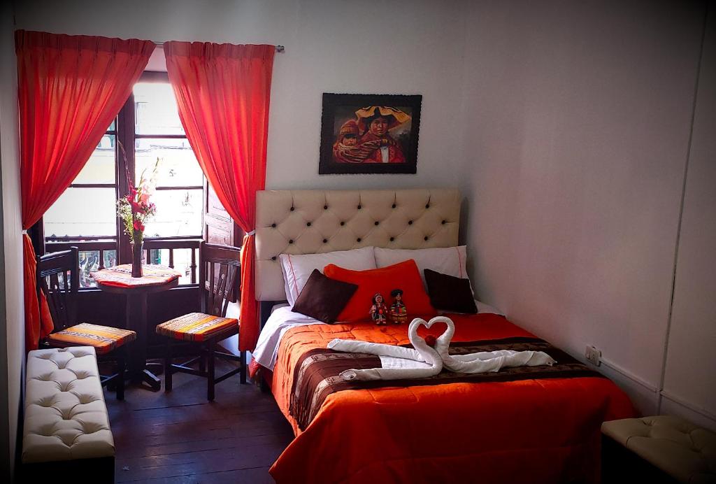 Un dormitorio con una cama roja con un cisne. en Imperial Golden House Inn, en Cusco