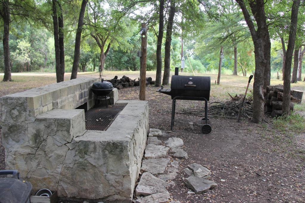 a grill and smoker in a park with trees at Fig Cabin in Fredericksburg