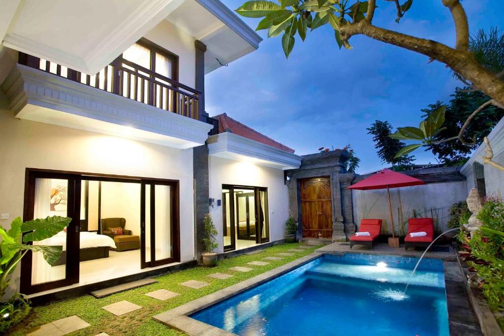 a villa with a swimming pool in front of a house at De' Bharata Bali Villas in Seminyak