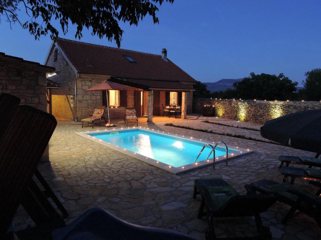 a swimming pool in front of a house at Villa Tihomir - with pool in Drniš