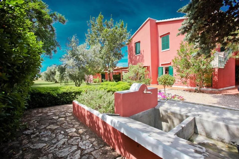 a house with a red building in the background at Agrialbergo Capalbio in Capalbio