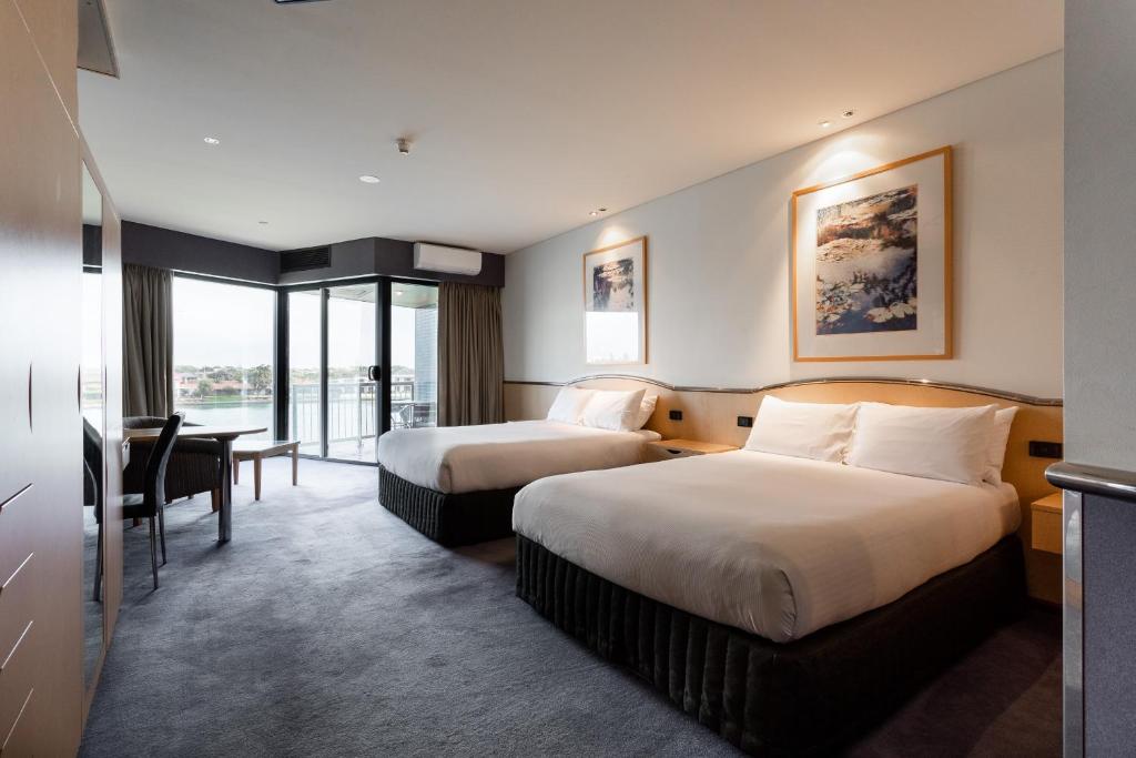 a hotel room with two beds and a desk at Lakes Hotel in Adelaide