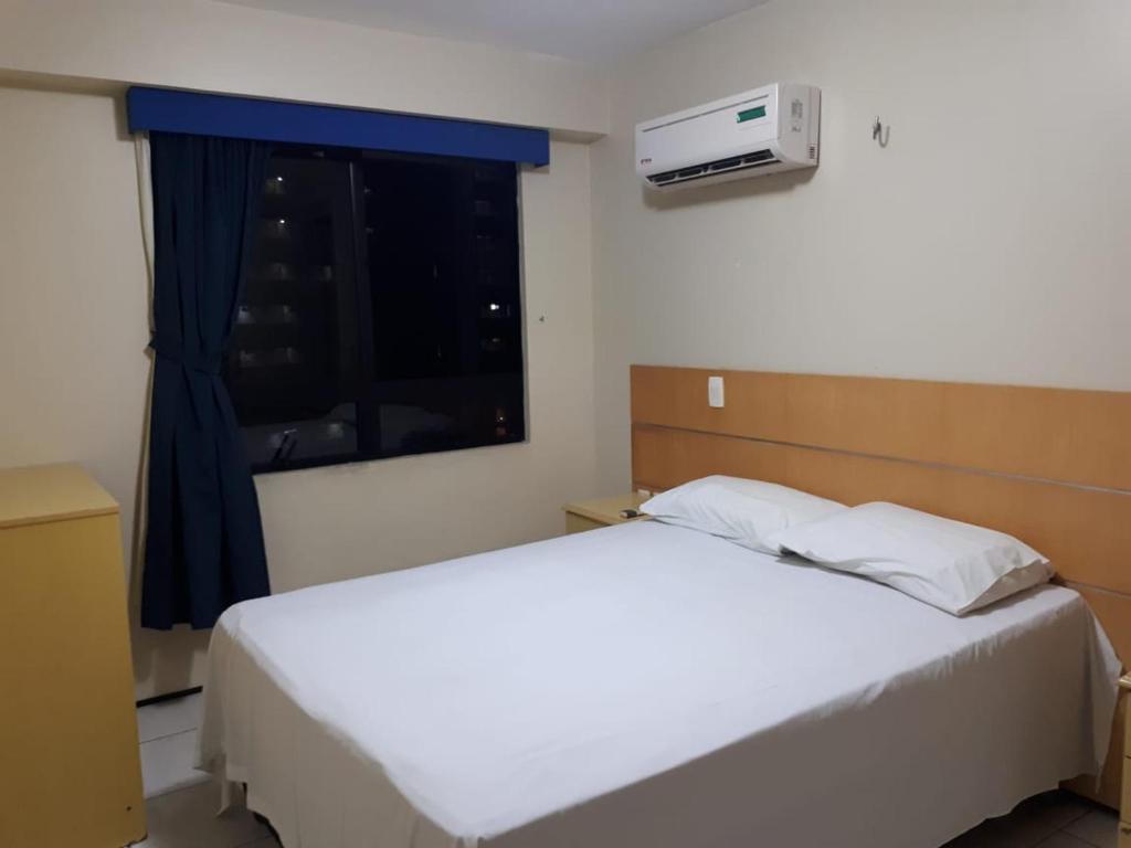 Apartamento em Fortaleza في فورتاليزا: غرفة نوم بسرير ابيض ونافذة