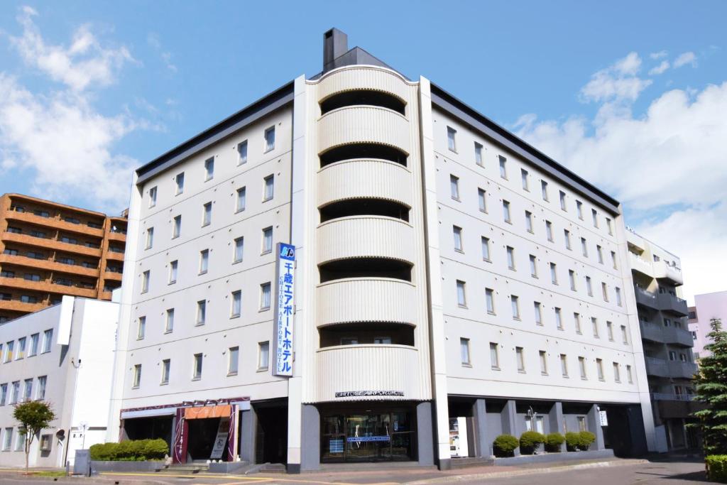 a white building with a sign on the front of it at Chitose Airport Hotel in Chitose