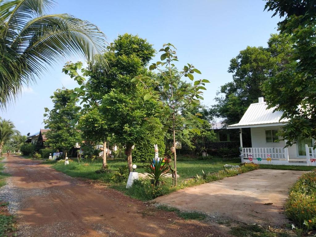 a house with a palm tree and a dirt road at Benjamat Resort in Sakon Nakhon