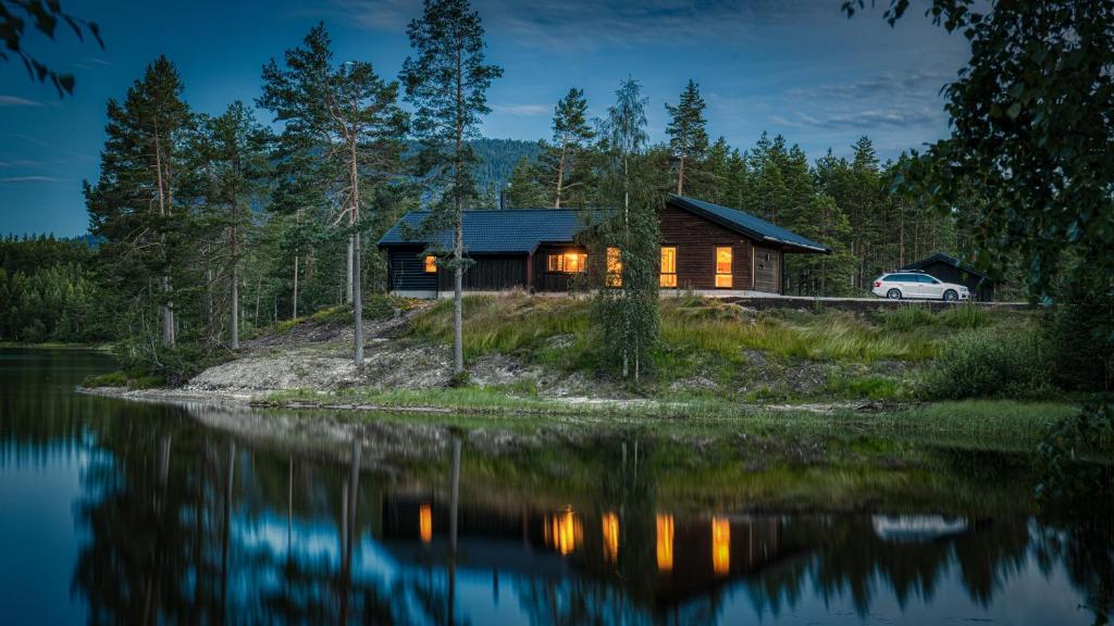 a cabin on the shore of a lake at night at Lakeside Haven Vrådal in Vradal