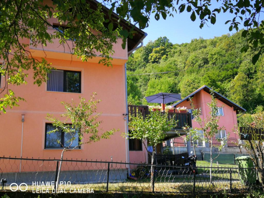 een roze huis met een paraplu en een terras bij Apartment Neo in Bihać