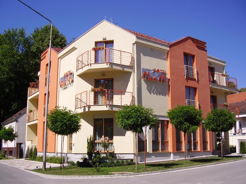 an apartment building with balconies and trees at Hotel Mladimir in Daruvar