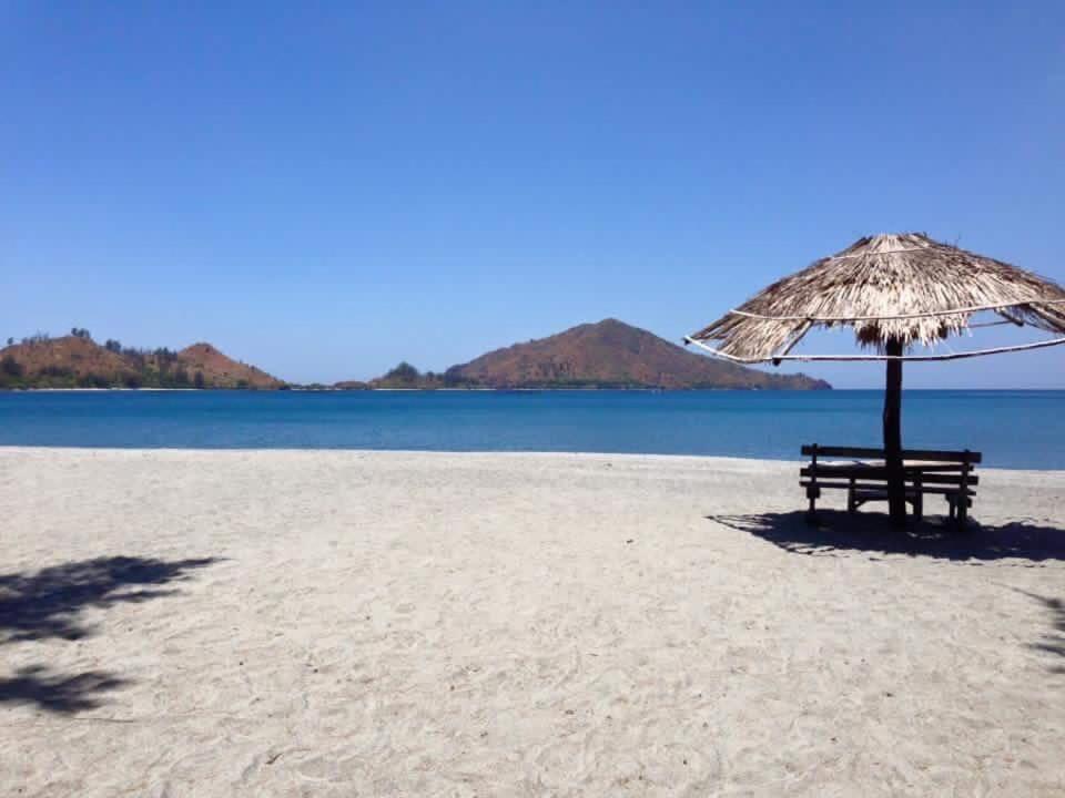 a bench sitting under an umbrella on a beach at Puerto Silanguin Beach Camping Resort in Zambales