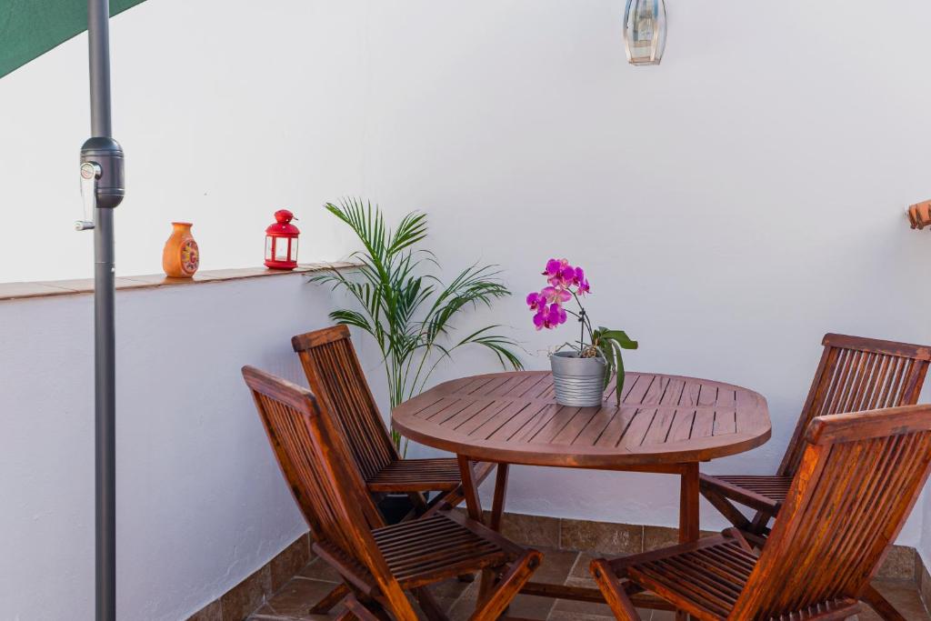 a wooden table and chairs with a table and flowers at La Buhardilla de Olivia in Málaga