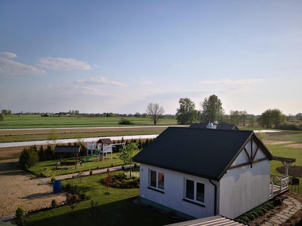 a small white house with a black roof at Letnisko nad jeziorem in Skulsk