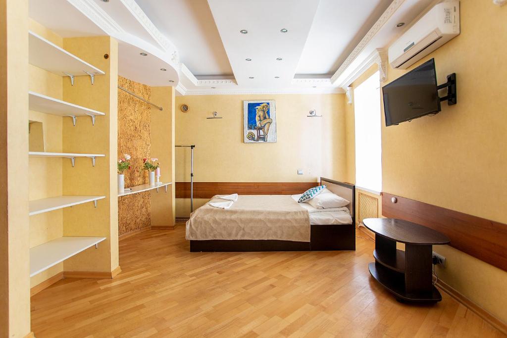 a room with a bed and a tv and shelves at Никитская капсула - сердце Москвы in Moscow