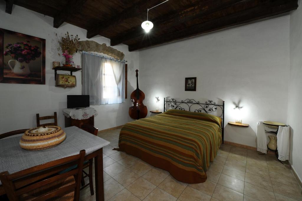 1 dormitorio con cama, mesa y guitarra en Locanda La Rosa, en Pauli Arbarei
