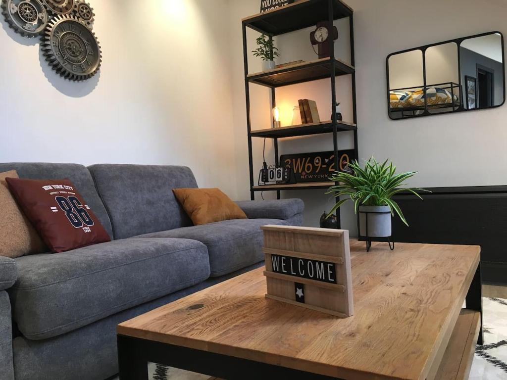 a living room with a couch and a table with a welcome sign at OFFRE SPECIALE Centre Verdun - Idéal Visites - Le Puisatier in Verdun