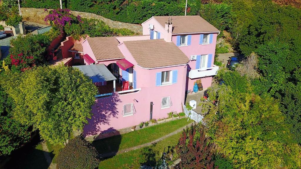 widok na różowy dom na wzgórzu w obiekcie Chambres d'hôtes Villa bella fiora w mieście Biguglia