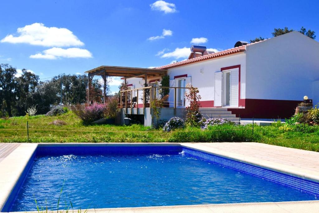 a house with a swimming pool in front of a house at Cal Velho - Holiday Lodge in São Luis