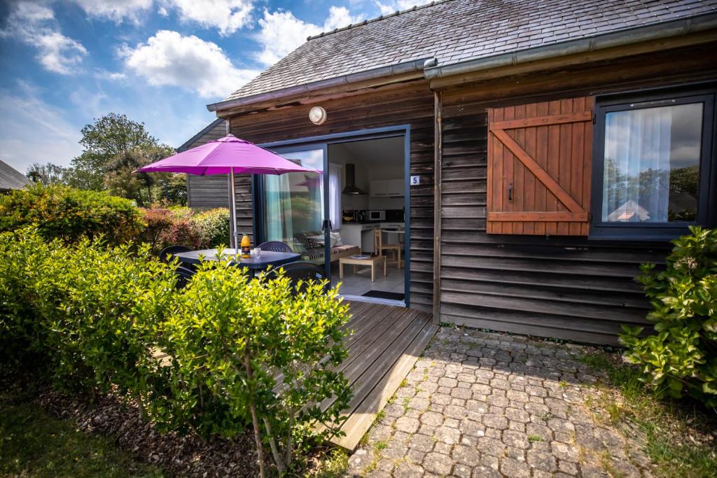 een huis met een houten terras met een paarse paraplu bij Village Beauséjour - Rêves de mer in Le Conquet