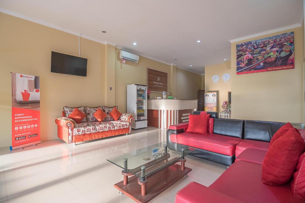 ein Wohnzimmer mit 2 Sofas und einem TV in der Unterkunft RedDoorz Plus near Syamsudin Noor Airport 3 in Banjarbaru