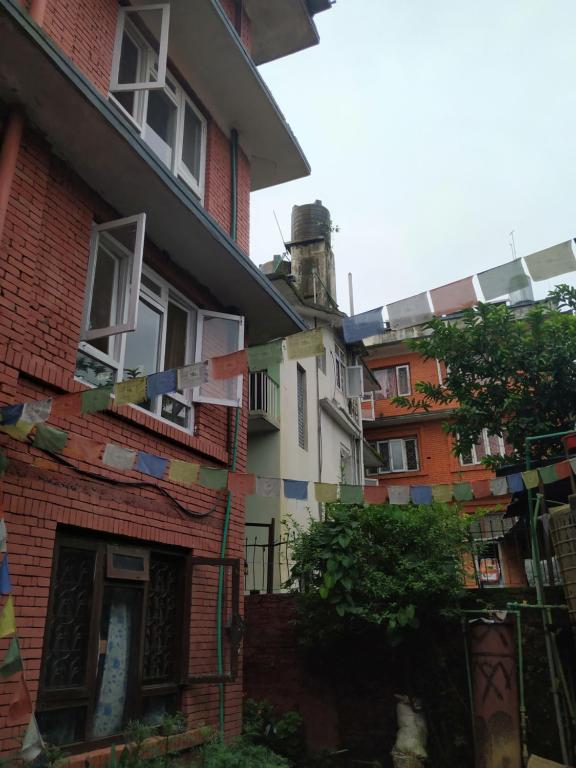 un grupo de edificios con banderas de oración delante de ellos en Family Peace House, Kathmandu, en Katmandú
