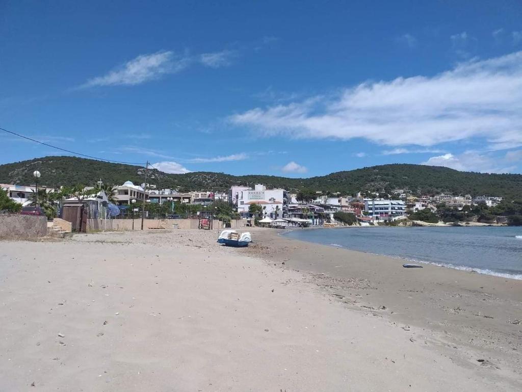 una playa con un barco sentado en la arena en agia marina riviera aigina, en Agia Marina Aegina