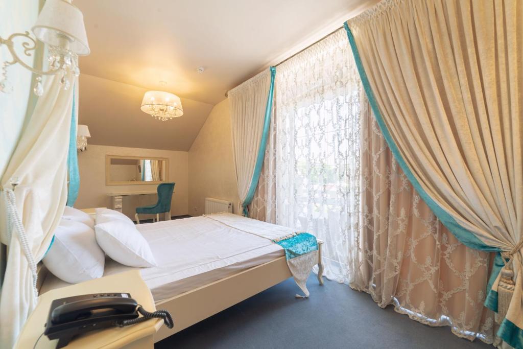 1 dormitorio con 1 cama y una ventana con cortinas en Гостиница Альвита Краснодар Центр, en Krasnodar