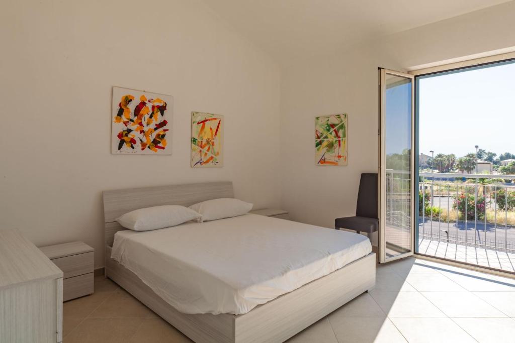 a white bedroom with a bed and a balcony at Nebrodi Park Private Villa in SantʼAgata di Militello