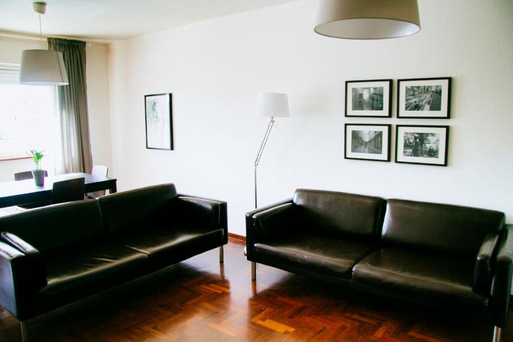 a living room with two black leather couches and a table at Typical Apartment in Lisbon, Campo Grande (Parking included) in Lisbon