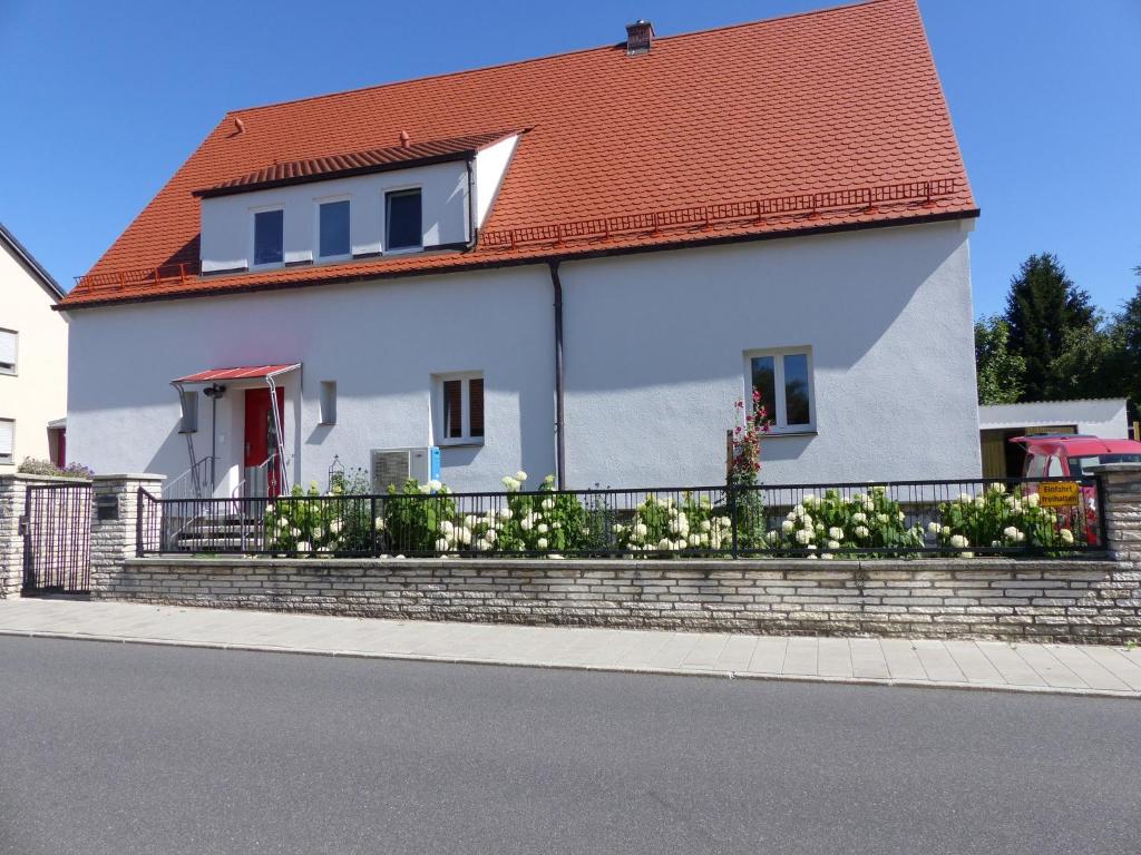 ein weißes Haus mit orangefarbenem Dach und einem Zaun in der Unterkunft Ferienwohnung Gretl & Xaver in Neumarkt in der Oberpfalz