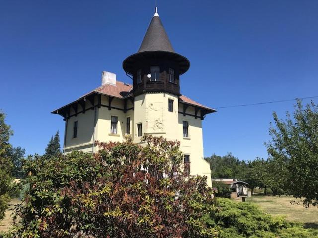 un bâtiment avec une tour au-dessus d'un champ dans l'établissement Penzion Vila E Landisch, à Chomutov