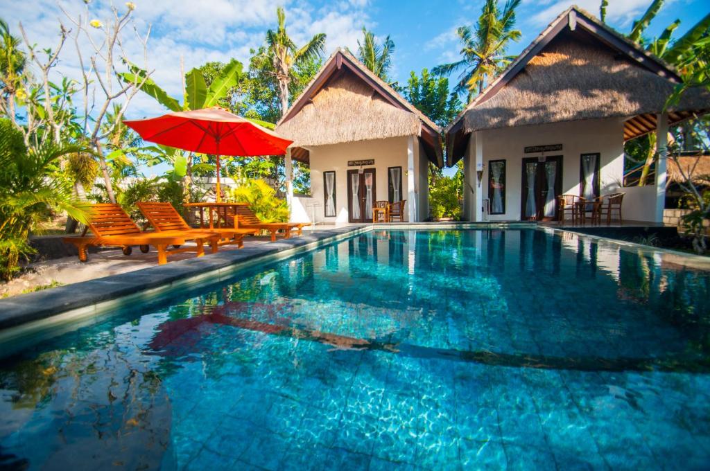 a villa with a swimming pool with a red umbrella at Japa Bungalow in Nusa Penida