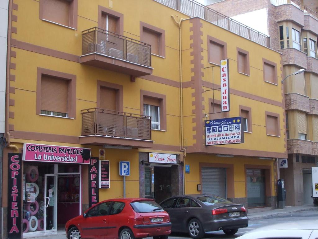 dos coches estacionados frente a un edificio amarillo en Hostal Casa Juan, en Lorca