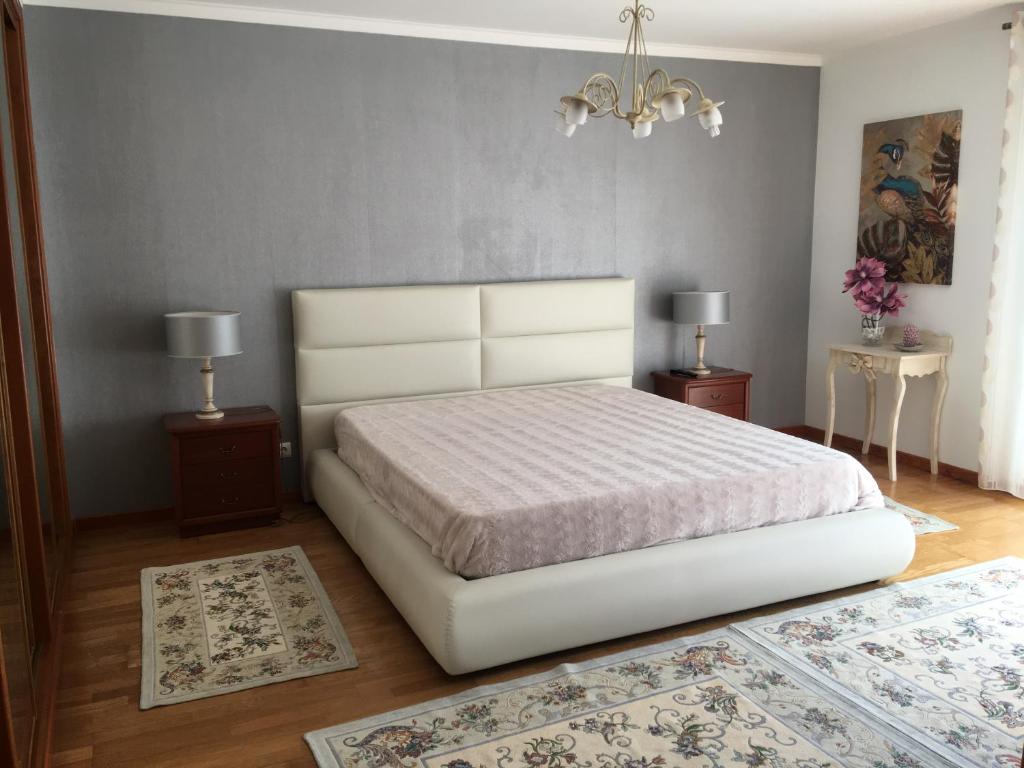 sypialnia z białym łóżkiem z dwoma stołami i dwoma dywanami w obiekcie Moradia Chicharro w mieście Nazaré