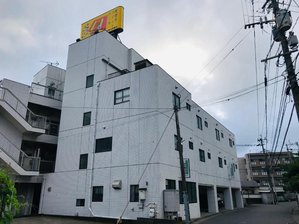 een wit gebouw met een bord erop bij Guesthouse & Hotel RA Kagoshima in Kagoshima