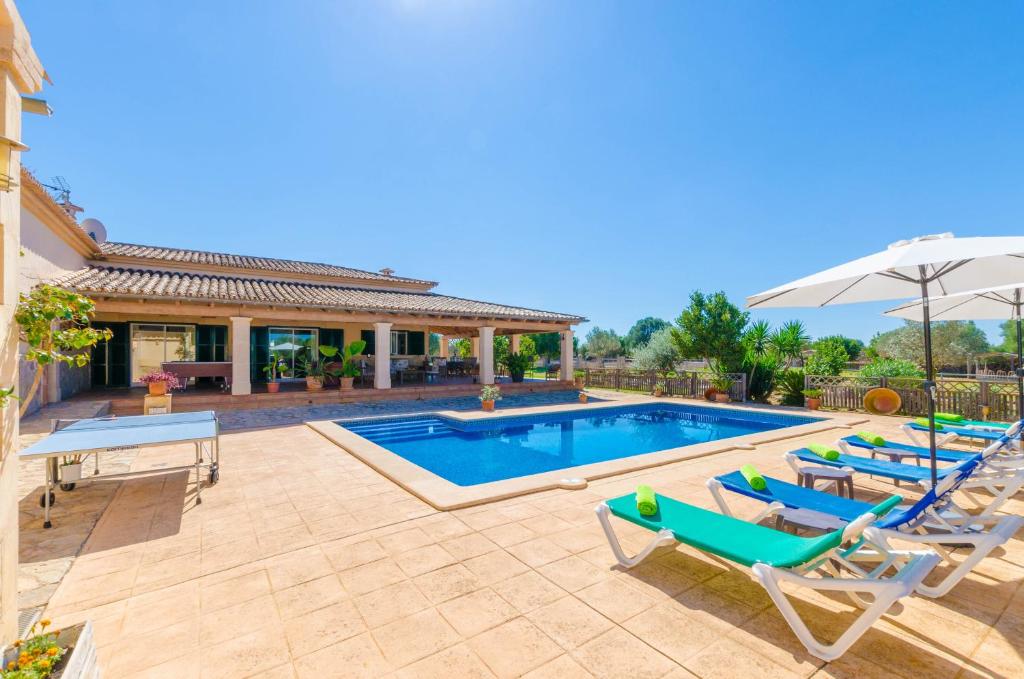 a swimming pool with lounge chairs and an umbrella at Na Poram in Llucmajor