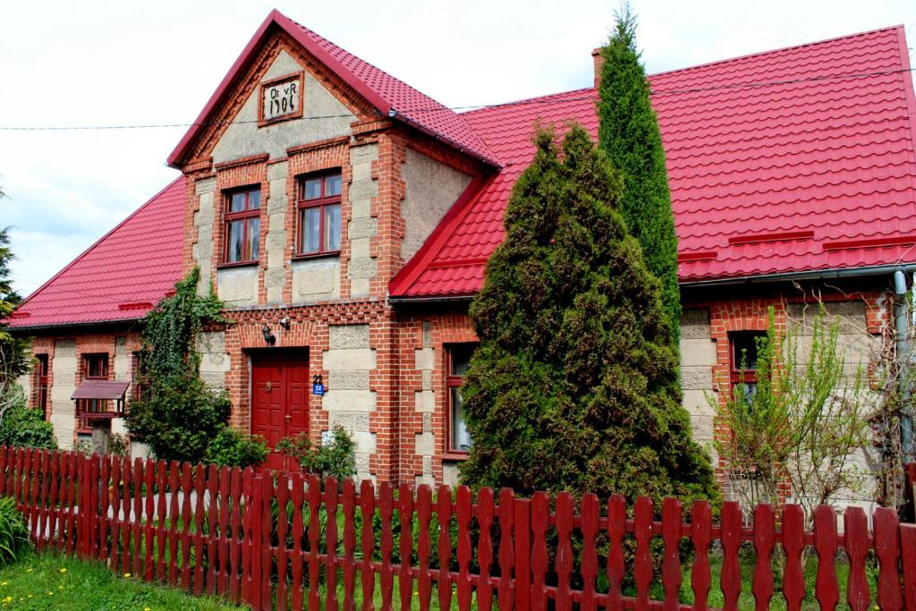 a house with a red roof and a red fence at Agroturystyka U Iwonki in Białowąs