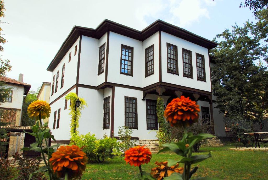 a white house with orange flowers in the yard at Mehves Hanim Konagi in Safranbolu