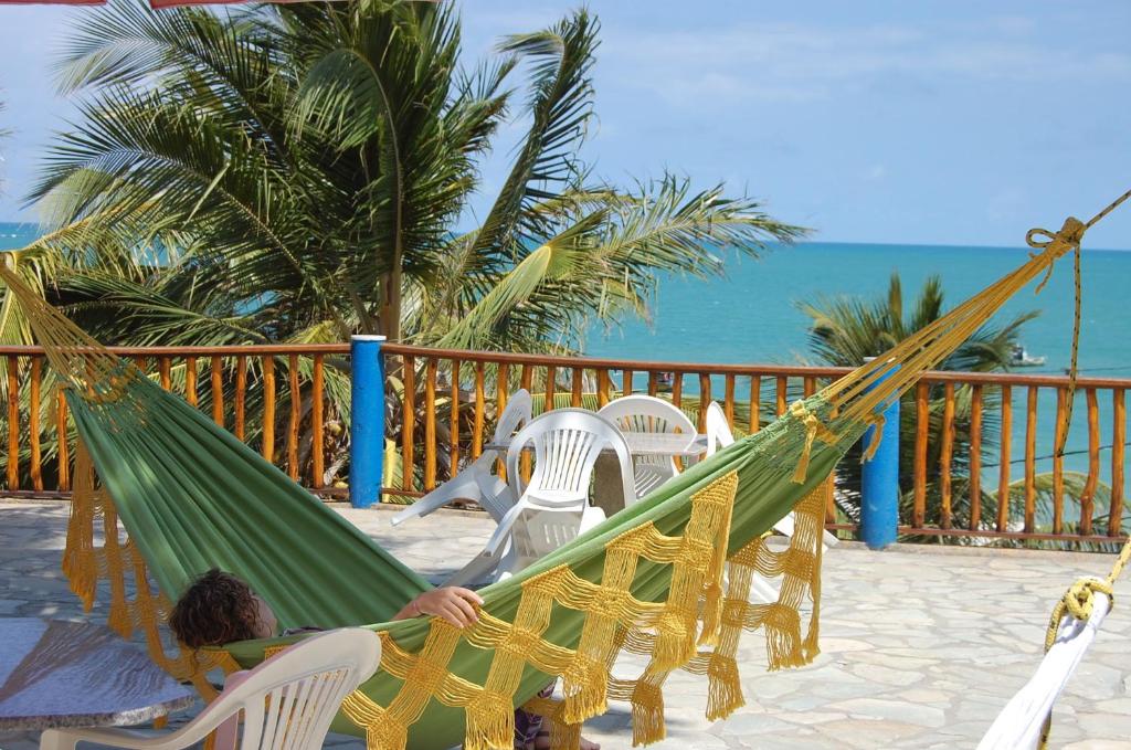 a person sitting in a hammock on a beach at Jacumã´s Lodge Hotel in Jacumã