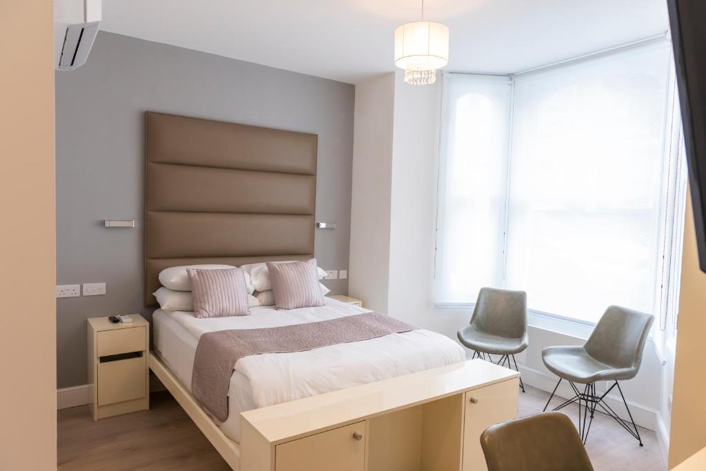 a bedroom with a large bed and two chairs at Messina Studios in London