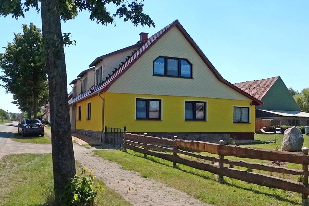 a yellow house with a fence in front of it at Ferienhaus mit 3 Schlafraeumen Vor in Woldegk