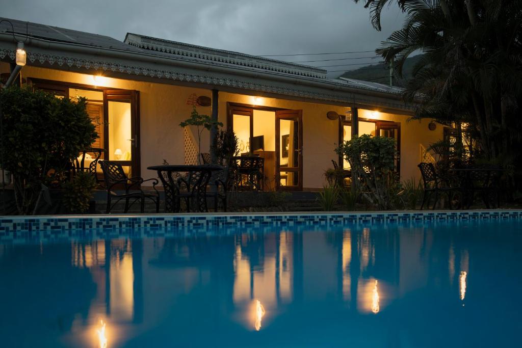 a swimming pool in front of a house at night at Auberge Chez Plume in Anse Boileau