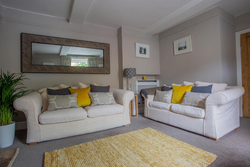 a living room with two white couches and a mirror at No. 14, Park Street in Stow on the Wold